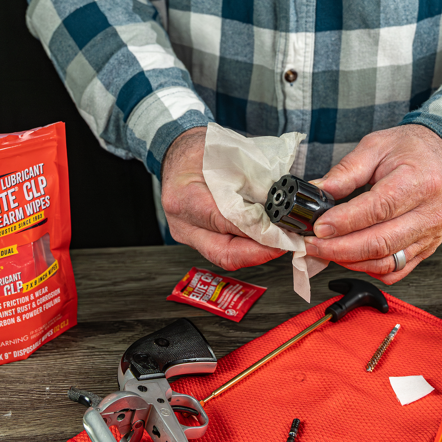 Image of Shooter's Choice FP-10 CLP wipes individually wrapped 12 count bag, with wipes in use on revolver cylinder